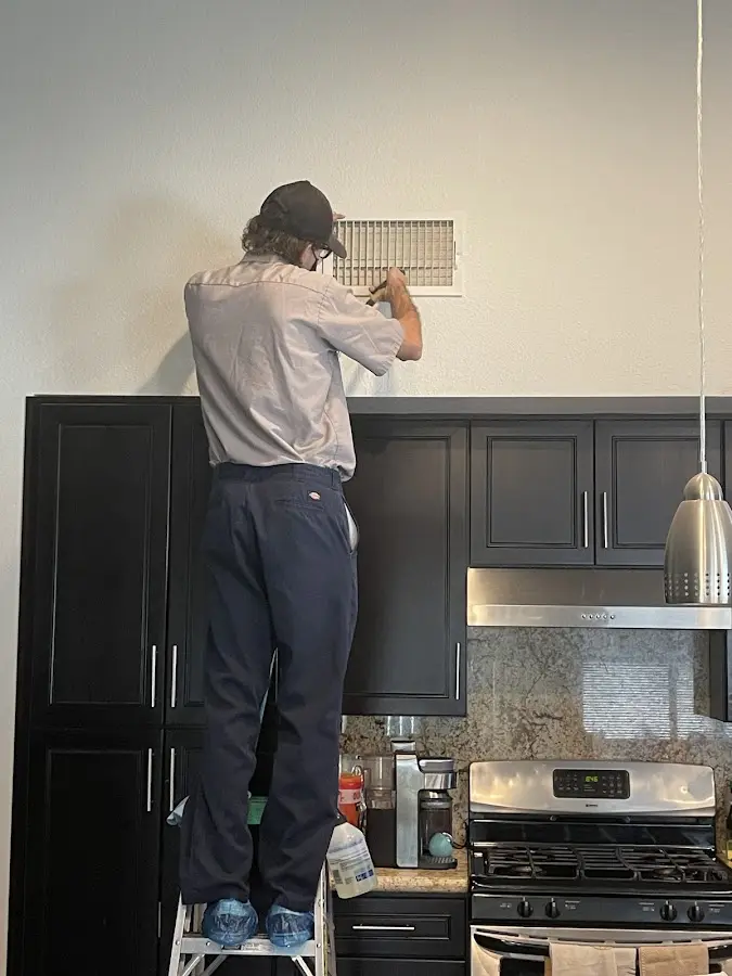 Technician inspecting an air vent during HVAC service in Thomasville